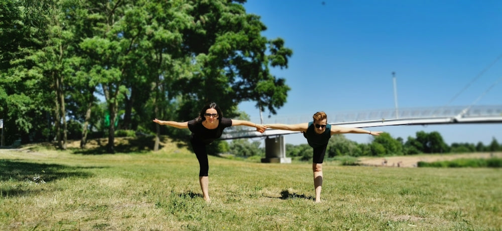 woman in black tank top and black shorts doing yoga on green grass field during daytime