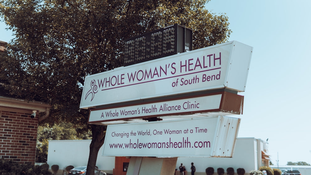 a sign with a tree in the background
