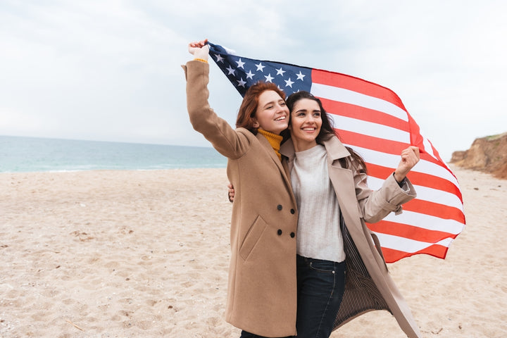 a couple of women standing on top of a sandy beach