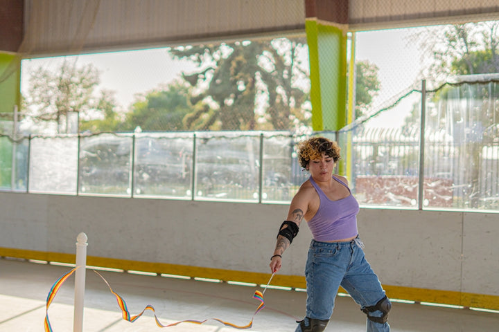A woman skates with a ribbon in a rink.