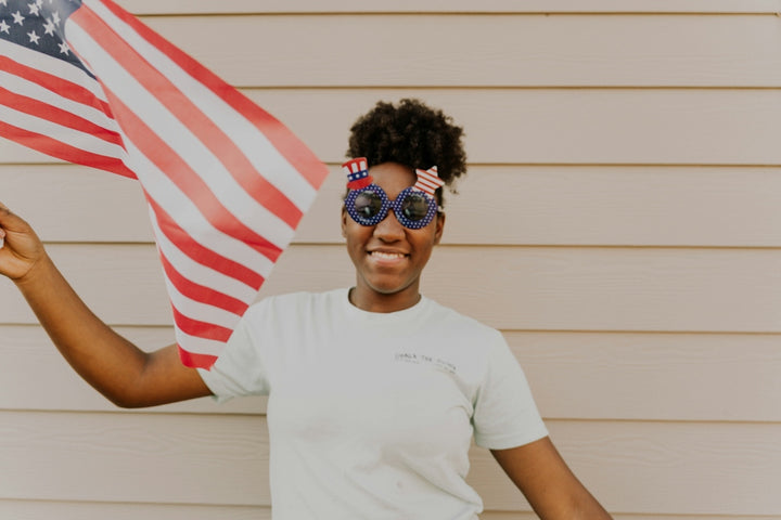 Girl celebrates with an american flag and sunglasses