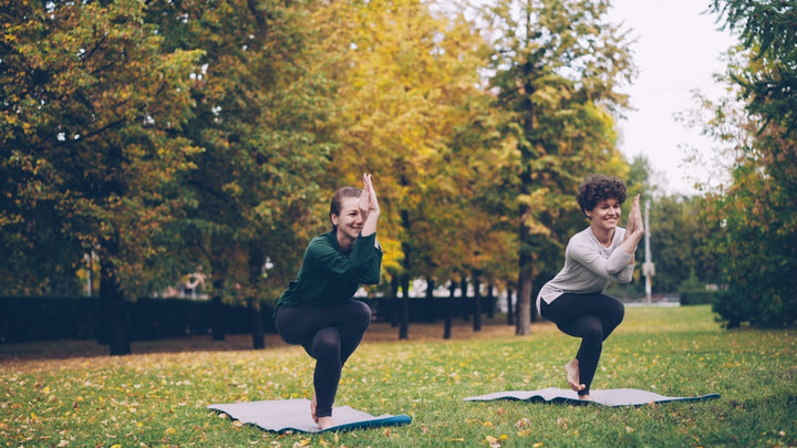 Two women practicing yoga in a park