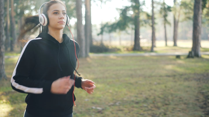 Young woman running in a forest wearing headphones