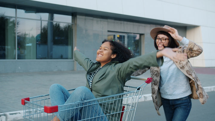 Two women joyfully riding in a shopping cart